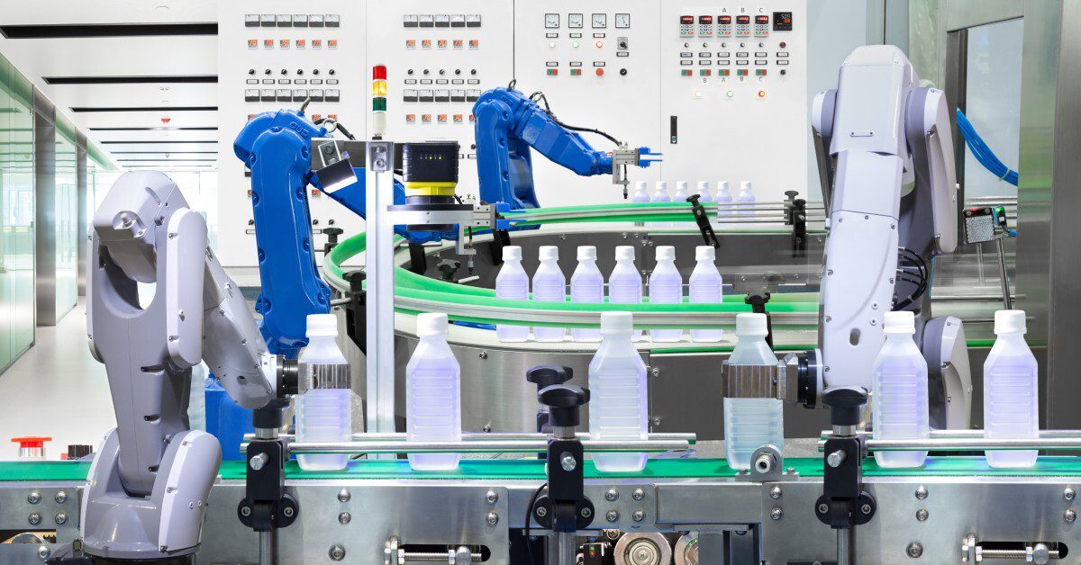 Automated production line with robotic arms handling clear bottles on conveyor belts in a clean, industrial facility.