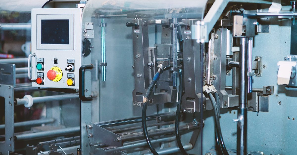 machine control panel with a digital display and colorful buttons, positioned along exposed metal mechanical parts.