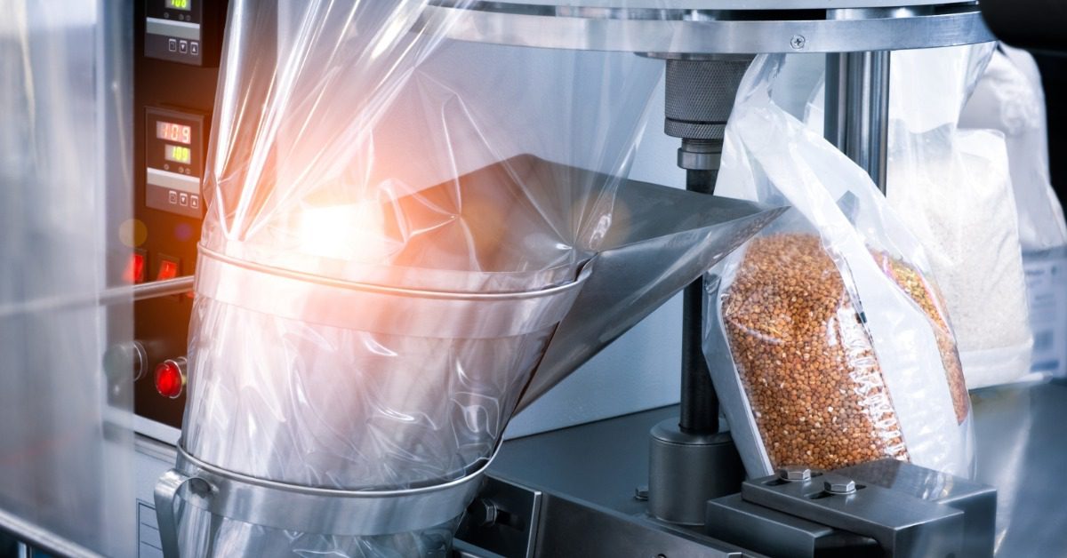 A conveyor packaging machine processing food products, with packaged items moving along a production line in a facility.