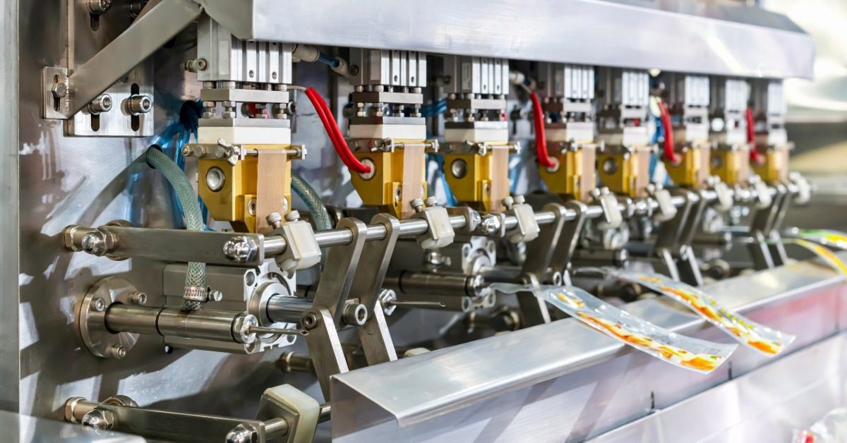 A horizontal filling machine with several nozzle dispensers. Several pouch packages are attached to the equipment.